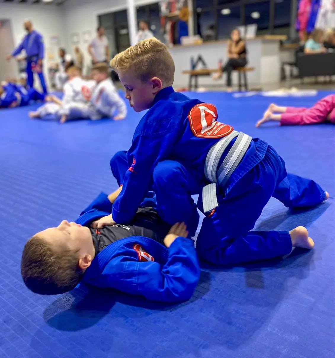Two young students practicing a position in a kids Jiu-Jitsu class.
